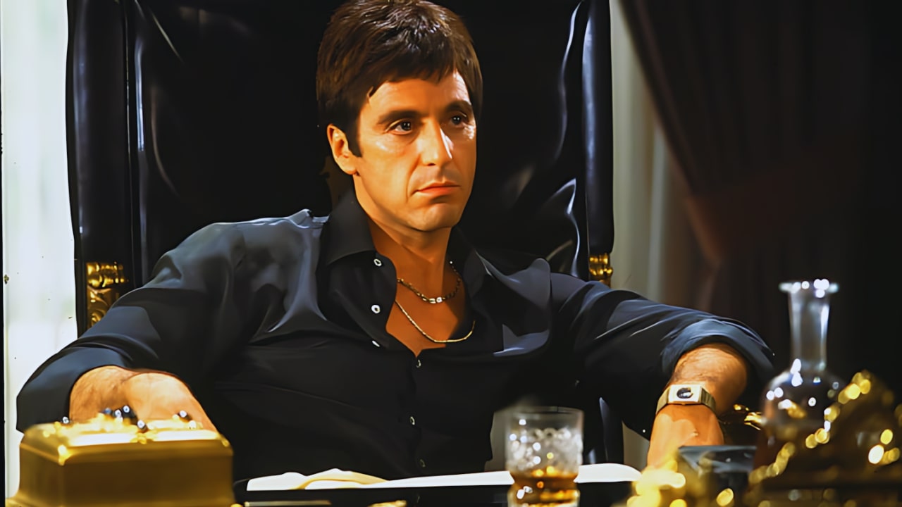 Tony Montana sitting on a black chair in the movie Scarface